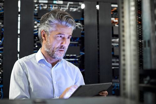 Technician working on a tablet in a server room.
